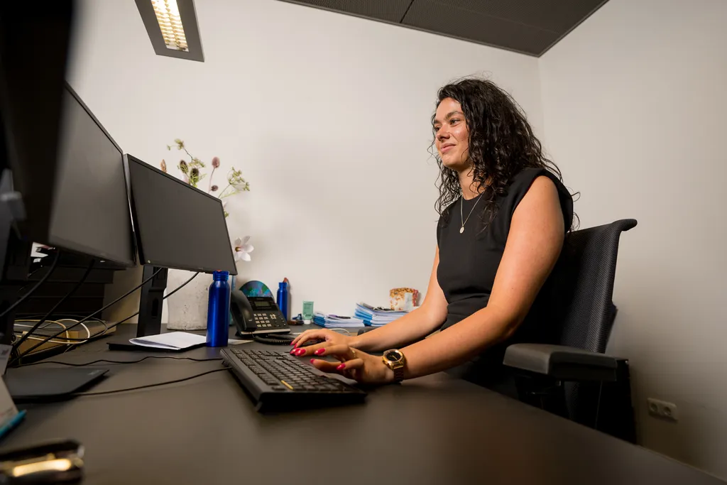 Jonge vrouw typt op toetsenbord aan bureau in kantoor