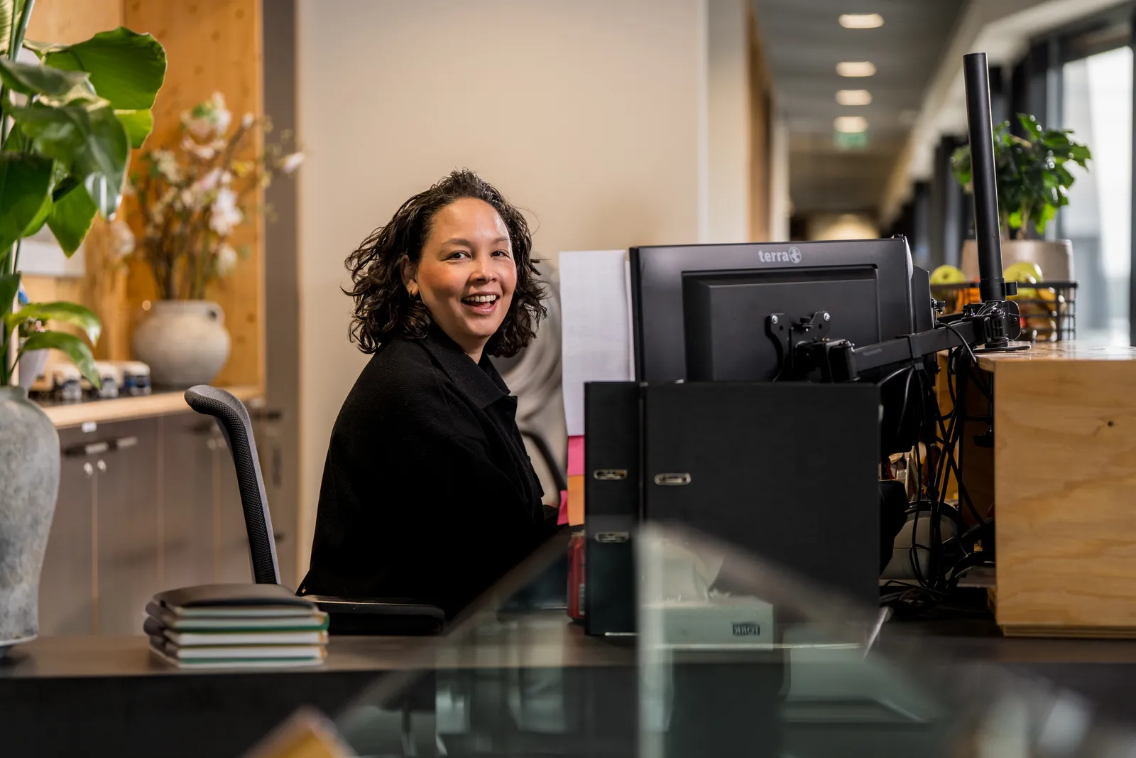 Versado medewerker zit achter haar bureau, lachend