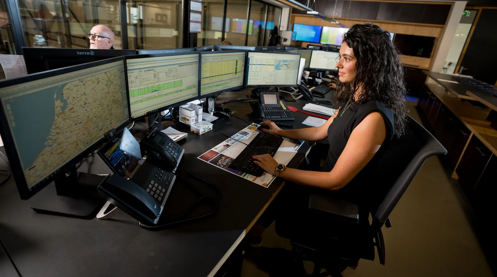 Medewerker achter bureau met veel beeldschermen
