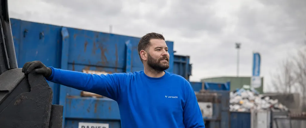 Medewerker afvalverwerking aan het werk bij containers onder een grijze lucht